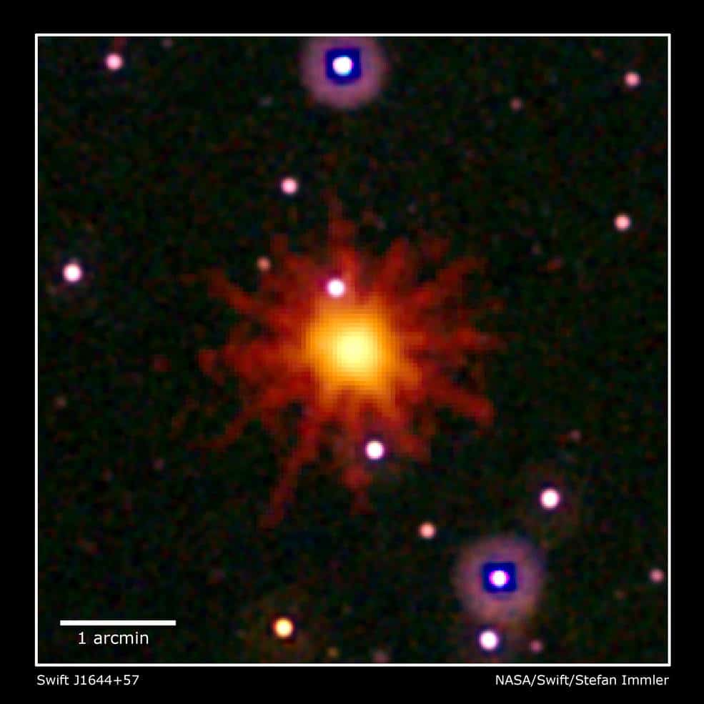 Imagens do Swift na faixa ultravioleta/óptico (branco, roxo) e de telescópios de raios-X (amarelo e vermelho) foram combinadas nesta composição do Swift J1644 + 57, uma irrupção de raio-X que os astrônomos classificam como um evento de interrupção das marés. O evento é visto apenas na imagem de raios-X, que é uma exposição de 3,4 horas tirada em 28 de março de 2011. A explosão foi desencadeada quando uma estrela passou muito perto de um buraco negro supermassivo. A estrela foi dilacerada, e grande parte do gás caiu em direção ao buraco negro. Até o momento, este é o único evento de interrupção das marés emissor de raios-X de alta energia que os astrônomos capturaram na luminosidade de pico. Créditos: NASA / Swift / Stefan Immler.