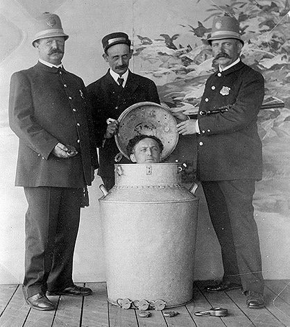Houdini momentos antes de realizar seu famoso número de escapismo, onde saía de dentro de um galão de leite trancado por cadeados. Créditos da Imagem: World History Project